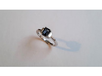 Centre emerald cut blue sapphire in a claw setting, with one baguette diamond each side.