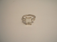Three stone ring set with centre emerald cut diamond, with a baguette diamond on each side in claw settings.