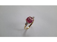 Three stone ring set with a centre pink sapphire and a trillion diamond either side.