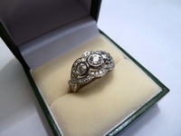 Palladium ring with three centre diamond rub over set and pave set diamond surround