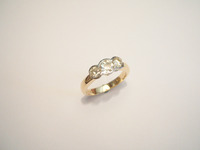 Yellow and white gold three stone diamond ring set with three round brilliant cut stones in a demi rubover setting.